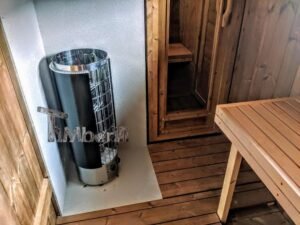 TimberIN Nordic Oval™ Terrace – udendørs sauna med terrasse, med synlige træbænke, synlig trædør og synlig saunaovn i metal
