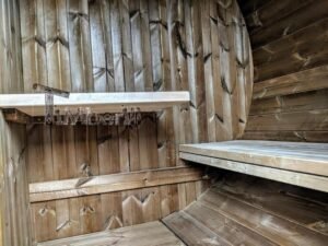 TimberIN Nordic Oval™ Terrace havesauna set indefra, med lange trinvise træbænke til højre, små hylder på bagvæggen og diagonalt året træbeklædning
