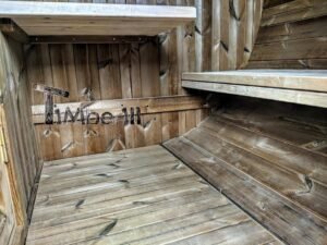 TimberIN Nordic Oval™ Terrace havesauna – blik mod gulvet indvendigt, med bred lægtebænk til højre, to vægplader til venstre og vejrbidt træbeklædning