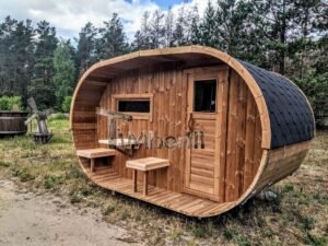 TimberIN Nordic Oval™ Terrace – udendørs sauna med terrasse, med synlige træbænke, synligt vindue og en bygning i baggrunden, på en åben eng