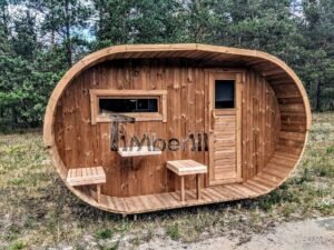 TimberIN Nordic Oval™ Terrace – udendørs sauna med terrasse, med synlige træbænke, synlig trædør, synligt vindue og gamle træer i baggrunden, i en anlagt have