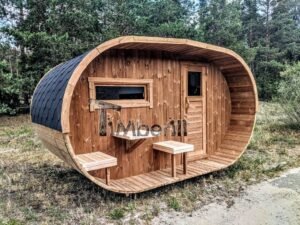 TimberIN Nordic Oval™ Terrace – udendørs sauna med terrasse, med indstigningstrappe i træ, synlige træbænke, synlig trædør og gamle træer i baggrunden