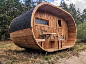 TimberIN Nordic Oval™ Terrace – udendørs sauna med terrasse, med synlige træbænke, synligt vindue og sort tag, i en anlagt have