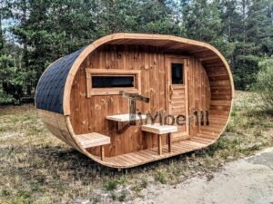 TimberIN Nordic Oval™ Terrace havesauna set skråt forfra tæt på, med ovalt halvtag, vandret vindue til venstre, lukket trædør til højre og udvendige hylder