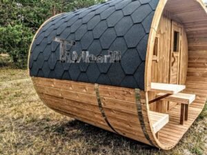 TimberIN Nordic Oval™ Terrace – udendørs sauna med terrasse, med indstigningstrappe i træ, synlig trædør og gamle træer i baggrunden, i en anlagt have