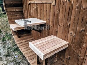 TimberIN Nordic Oval™ Terrace – udendørs sauna med terrasse, med synlige træbænke, i en anlagt have