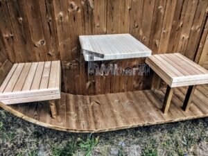 TimberIN Nordic Oval™ Terrace – udendørs sauna med terrasse, med synlige træbænke og havebord i nærheden, i en anlagt have