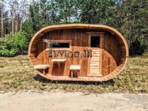 TimberIN Nordic Oval™ Terrace – udendørs sauna med terrasse, med synlige træbænke, synlig trædør og gamle træer i baggrunden, på en åben eng i en anlagt have
