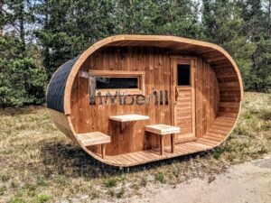 TimberIN Nordic Oval™ Terrace – udendørs sauna med terrasse, med synlige træbænke, synlig trædør, synligt vindue og gamle træer i baggrunden