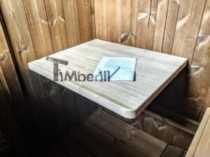TimberIN Nordic Oval™ Terrace sauna – lille klapbar træhylde på den mørke indervæg, med et informationsark og en blå kuglepen lagt på