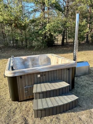 TimberIN Nordic Square™ Acryl – kvadratisk vildmarksbad i akryl, med indstigningstrappe i træ og gamle træer i baggrunden