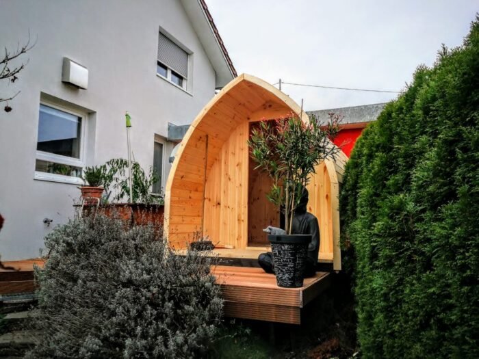 Igloosauna i træ med glasdør på en terrasse i haven