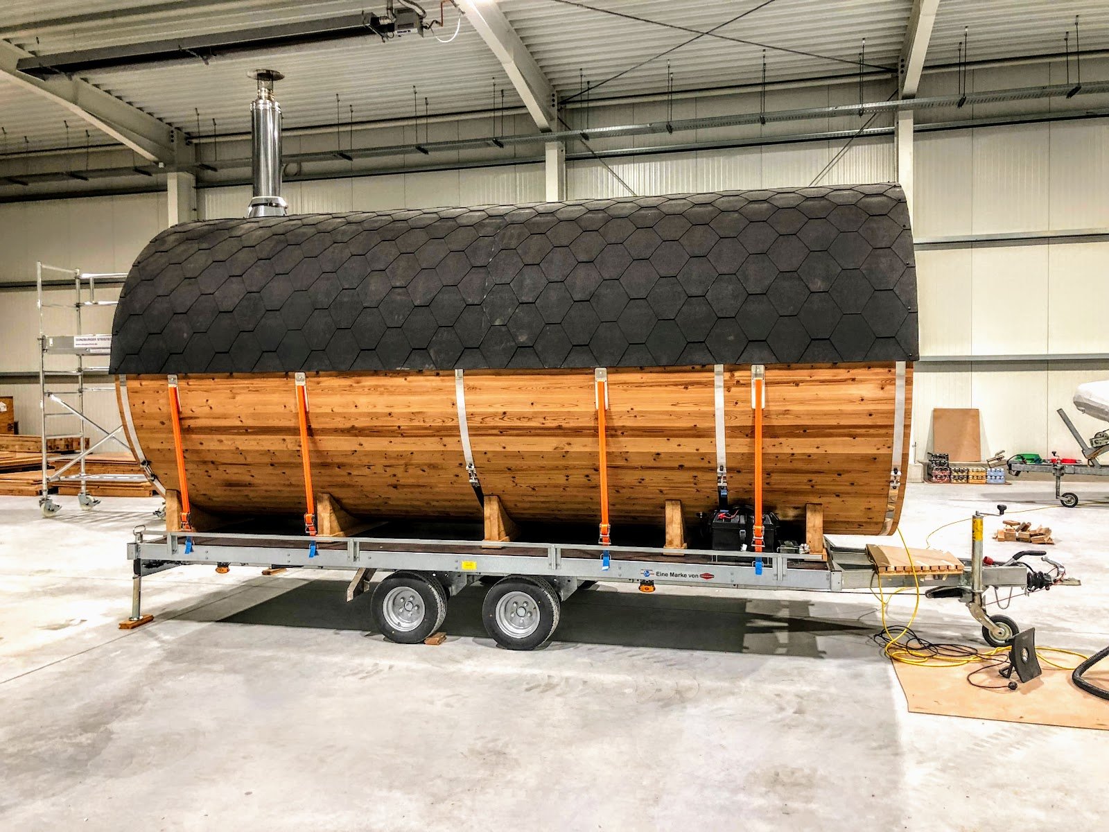 Mobil tøndesauna med sort tag monteret på en toakslet trailer