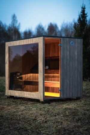 TimberIN Nordic Cube udendørs sauna med glasfront i skumringen