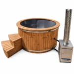 TimberIN Nordic™ External Comfort – rundt vildmarksbad med grå indsats, termotræbeklædning, trætrappe og ekstern brændeovn i rustfrit stål med skorsten på hvid baggrund.